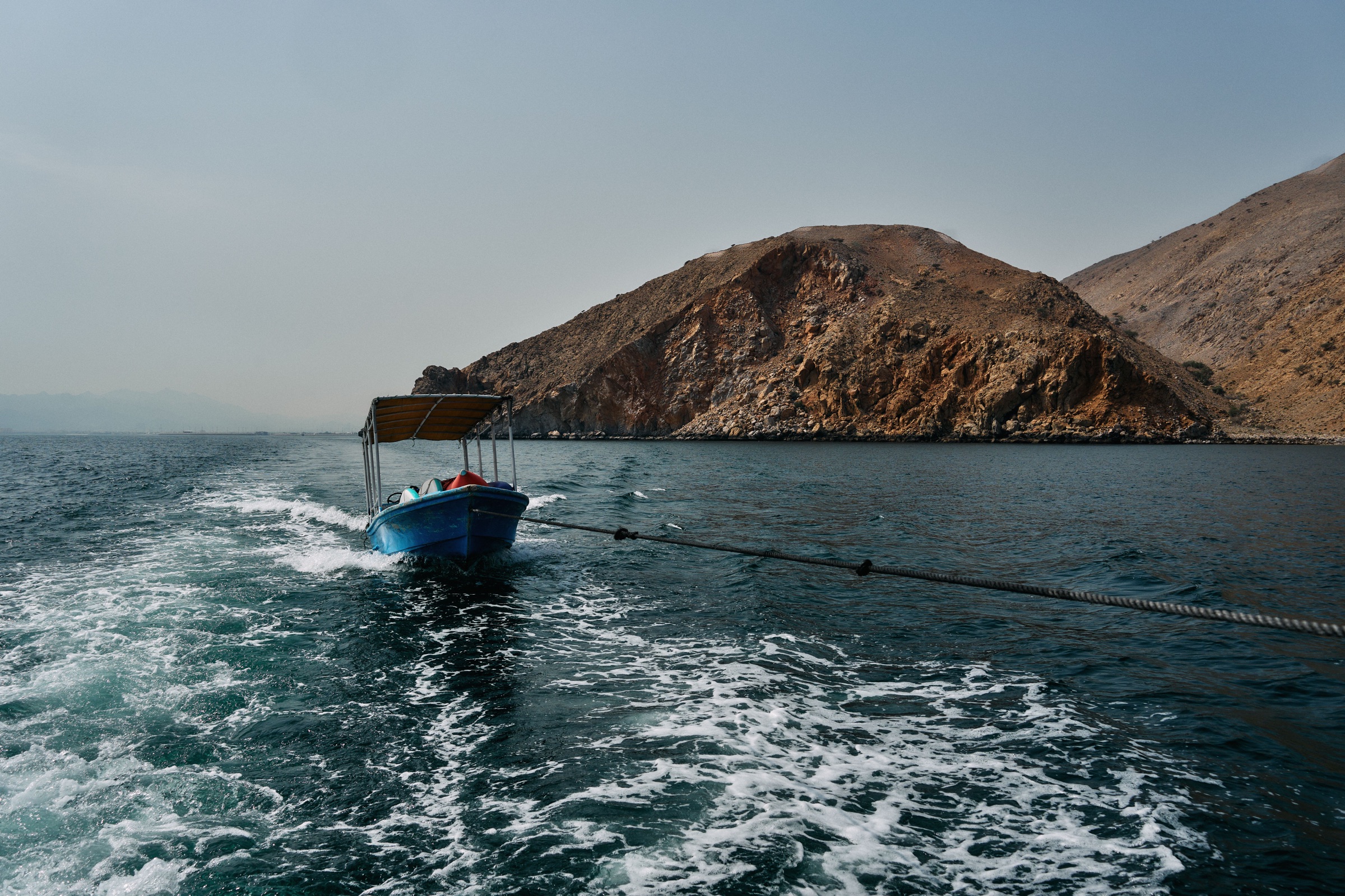 A boat travelling along Oman’s mountainous coastline